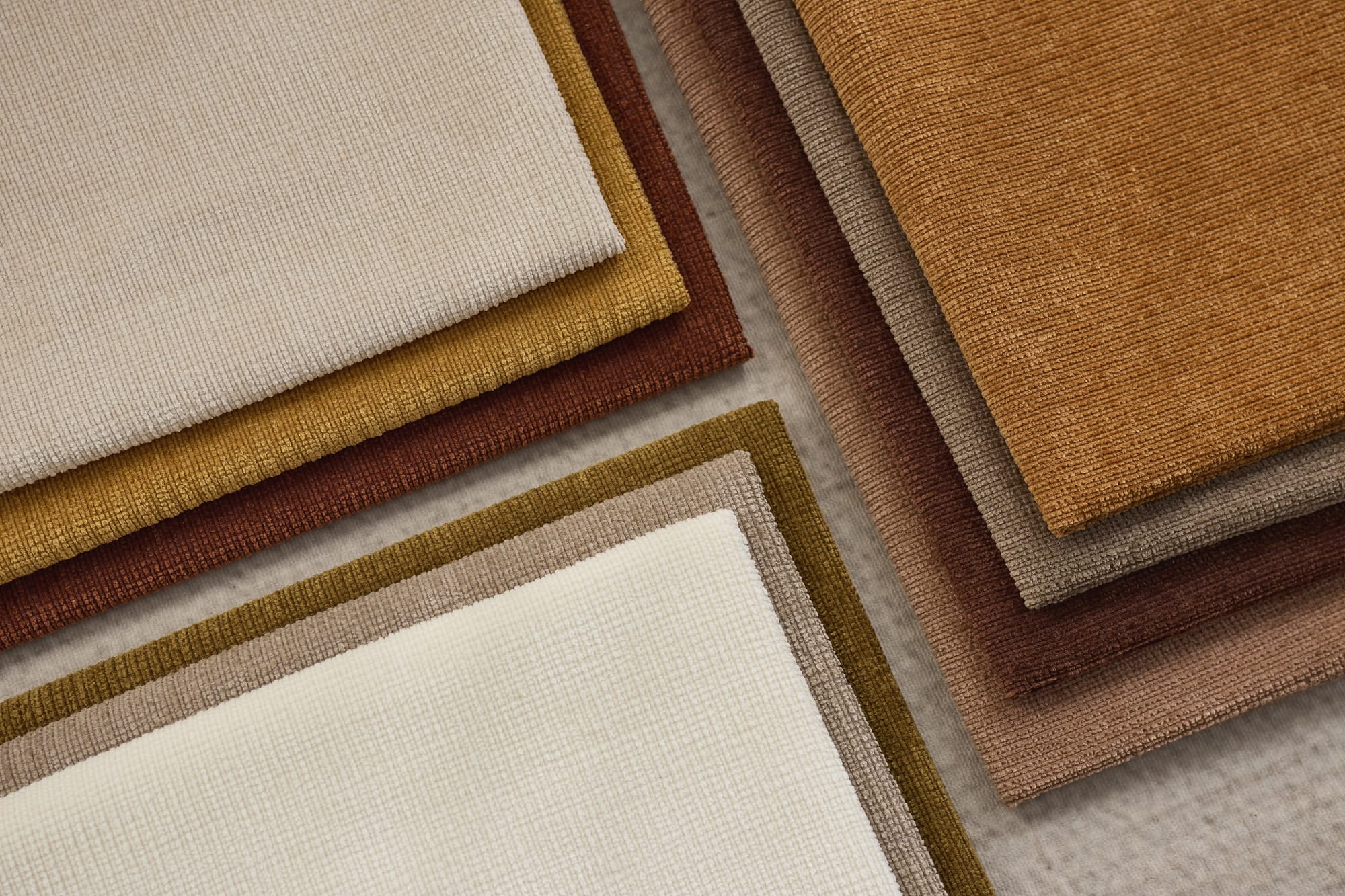 Layered woven fabric edges in cream, camel and brown, seen from above