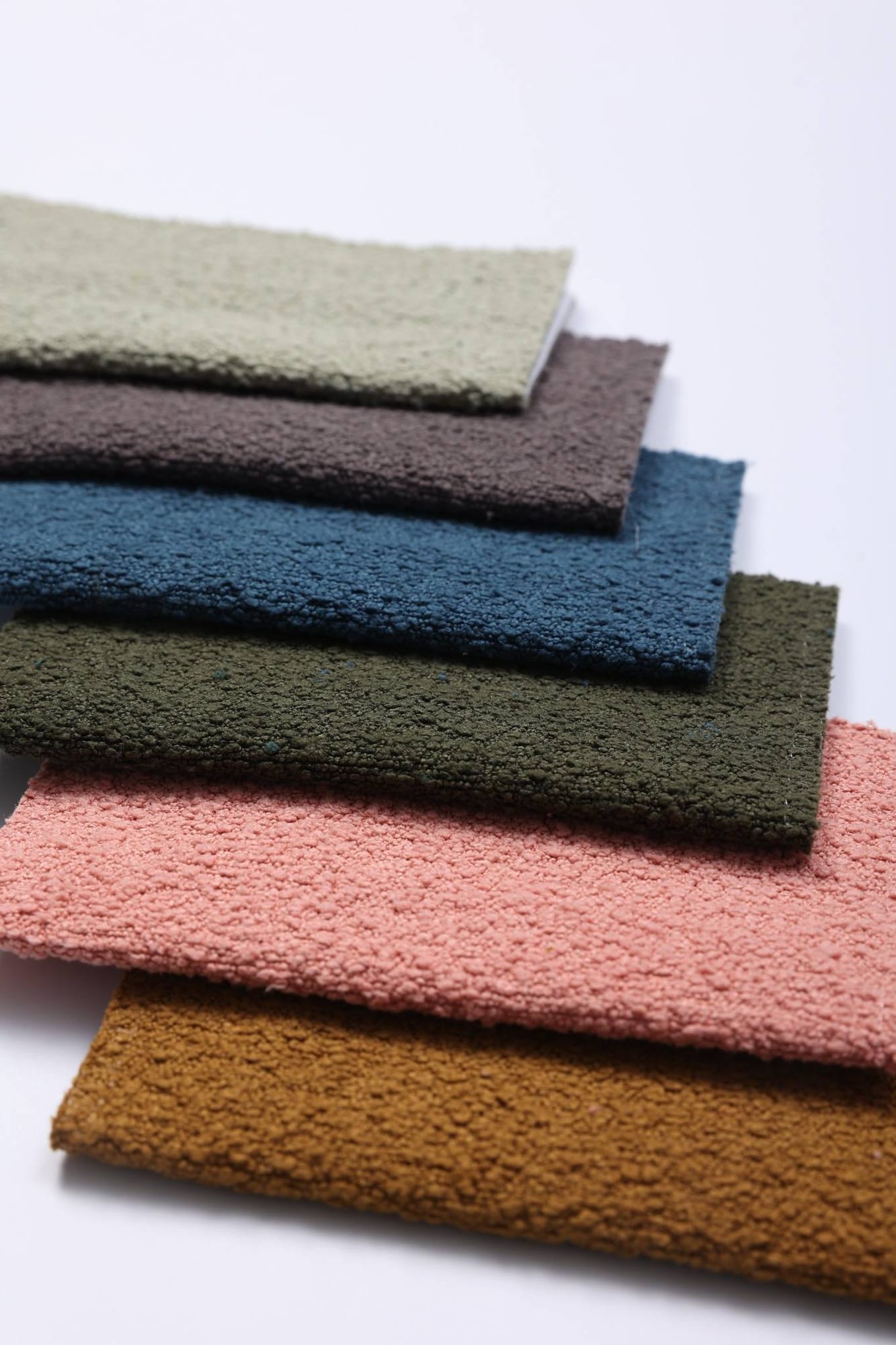 Stacked woven swatches in sage, taupe, teal, olive, coral and ochre