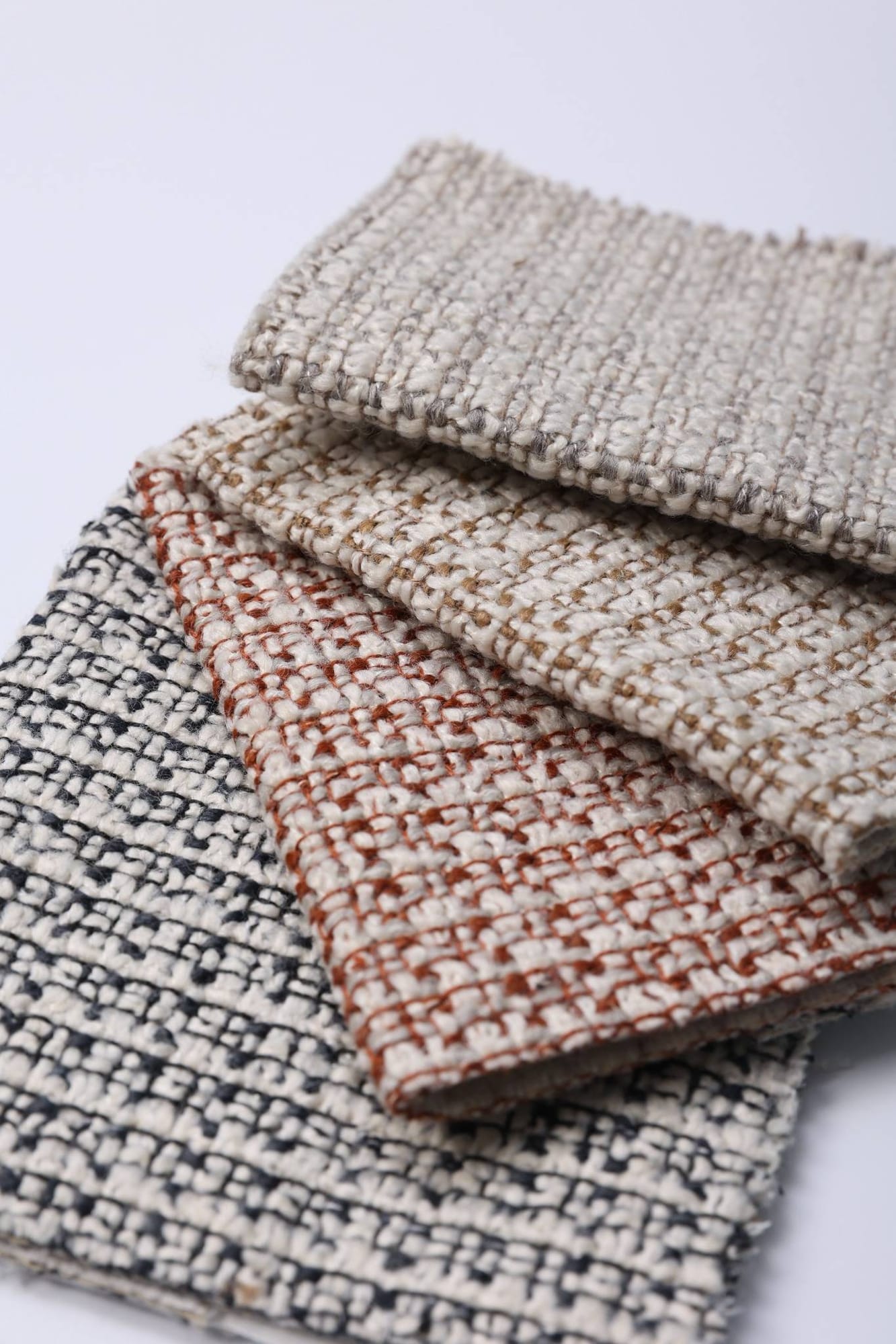 Overlapping woven swatches with a small two-tone pattern in grey and rust